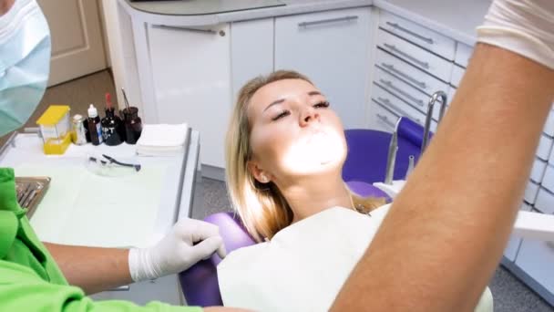 4k filmato di bella donna bionda seduta sulla sedia del dentista e apre la bocca per l'ispezione dei denti — Video Stock