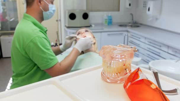 Imágenes 4k de la cámara centrada en la mesa con modelo de teel de plástico y gafas UV protectoras, mientras que el dentista trata los dientes de los pacientes — Vídeos de Stock