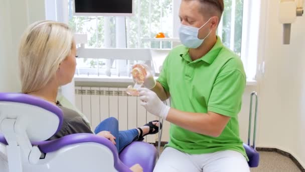 Imagens 4k de dentista mostrando modelo plástico de dentes para seu paciente — Vídeo de Stock