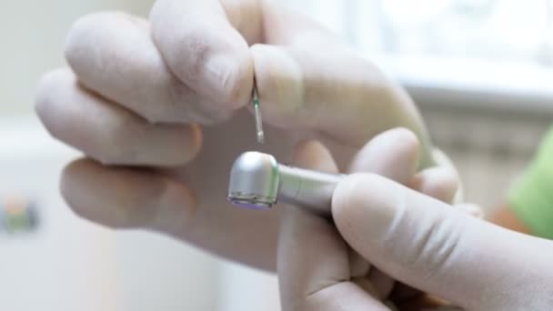 Primer plano 4k metraje del dentista en guantes quirúrgicos protectores insserting bit en taladro dental — Vídeo de stock