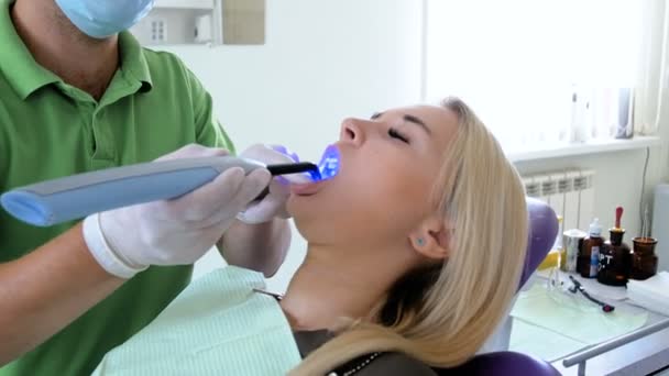 Primer plano 4k metraje del dentista utilizando fotopolímero UV y lámpara para el curado de dientes — Vídeos de Stock