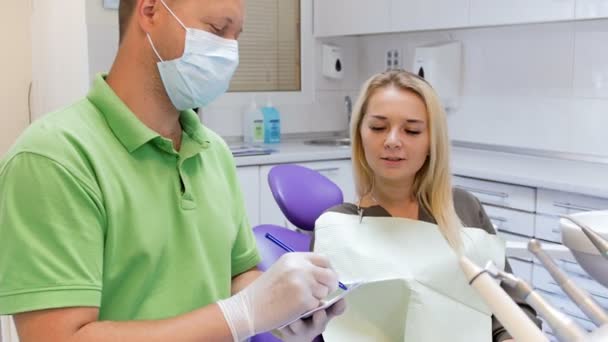 4k відео чоловічого стоматолога, який пише рецепт на папері для свого пацієнта — стокове відео