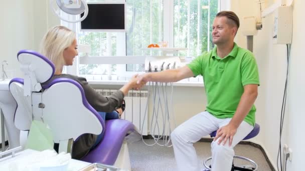 Imágenes de 4k de la joven feliz estrechando la mano con el dentista y saliendo de la oficina del dentista — Vídeo de stock