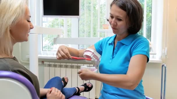 Filmagem em 4k de uma dentista explicando a importância da higiene dos dentes para sua paciente — Vídeo de Stock