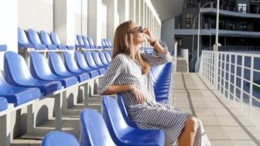 şık genç kadına dinlendirici boş Stadyumu parlak güneşli bir günde, 4 k görüntüleri