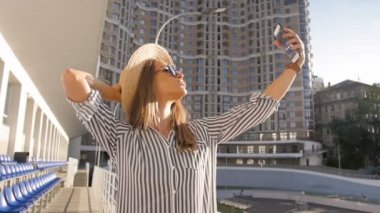 Ağır çekim video selfie sıcak güneşli gün yapma güneş gözlüğü içinde mutlu gülümseyen kadın tonda
