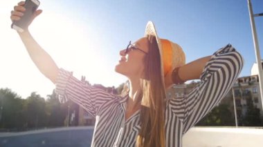 Şapka ve güneş gözlüğü selfie üstünde hareket eden telefon yapma gülümseyen kadın Slow motion video