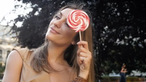 Close up 4k video of cute woman posing and playing with lollipop — стоковое видео