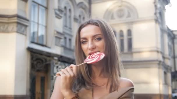 Vidéo 4k de jeune femme heureuse jouant et dansant dans la rue avec sucette rouge — Video