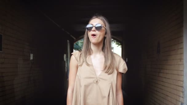 4k відео стильної молодої жінки, що стоїть на вулиці і дме бульбашки жувальної гумки — стокове відео