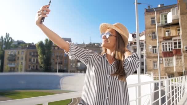 Slow motion video av snygg ung kvinna att göra selfie på gatan på solig dag — Stockvideo