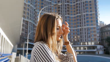 Güzel genç esmer kadının rüzgarlı güneşli gün, sokakta Slow motion video