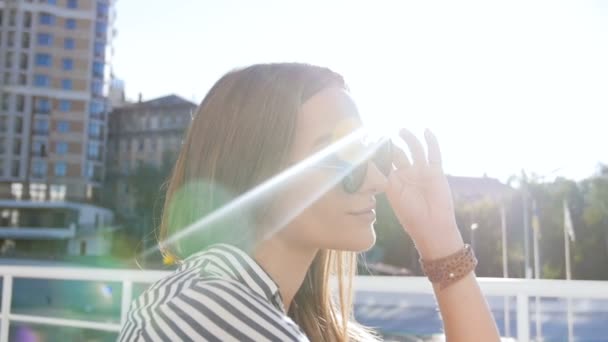 Slow-motion video van mooie jonge vrouw in zonnebril poseren op straat — Stockvideo