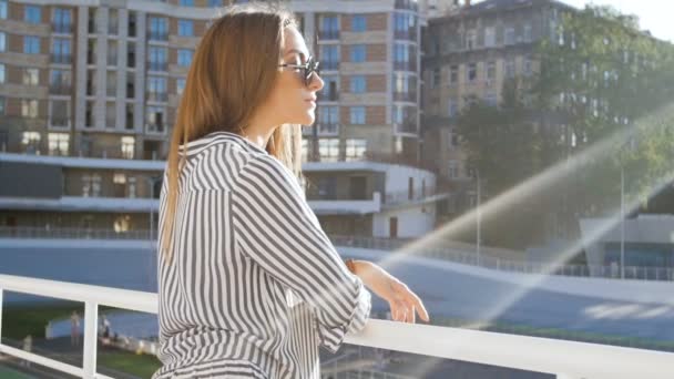 Медленное видео стильной молодой женщины в солнечных очках, стоящей на улице в солнечный день — стоковое видео