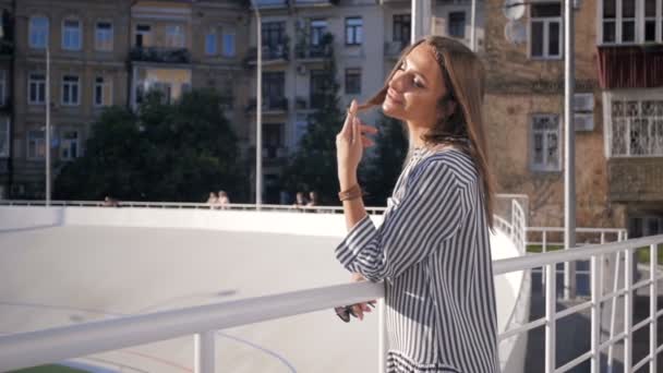 Zeitlupenvideo einer stilvollen brünetten Frau, die vor urbanem Hintergrund posiert — Stockvideo