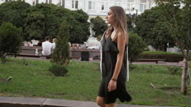 Genç kadın kısa siyah şık elbise Park'ta yürüyordunuz Slow motion video