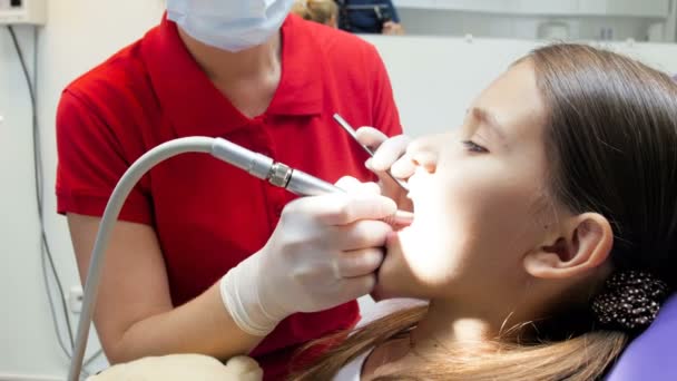 Primer plano 4k metraje del dentista usando taladro dental mientras trata los dientes de los adolescentes — Vídeos de Stock