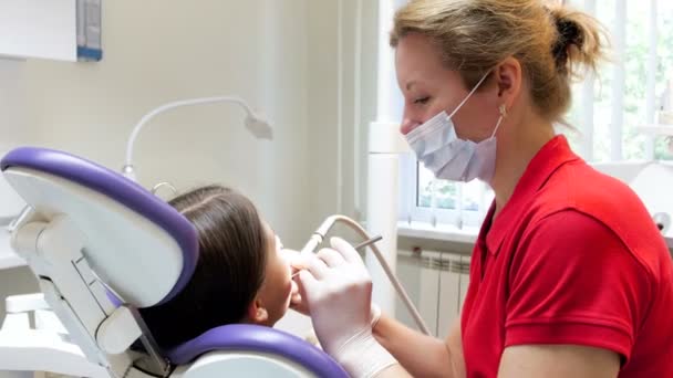 Primer plano 4k metraje del dentista tratando los dientes de las niñas y la eliminación de la caries — Vídeo de stock