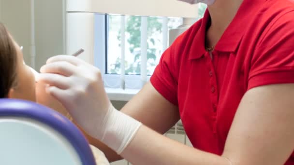 Panoramique vidéo 4k du dentiste en masque chirurgical et masque de protection traitant le patient — Video