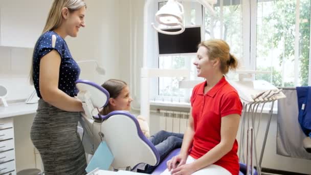 4 k beelden van vrouwelijke tandarts in gesprek met jonge moeder en tiener meisje zit in tandheelkundige stoel — Stockvideo