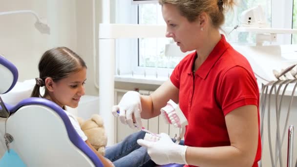 4k відео стоматолога, який навчає свого пацієнта-підлітка правильно чистити зуби зубною щіткою — стокове відео