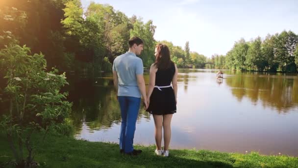 Vídeo em câmera lenta de belo jovem tendo encontro com a namorada junto ao lago na floresta — Vídeo de Stock