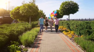 4 arkadaşlar renkli balonları Park'ta yürüyüş ağır çekim görüntüleri