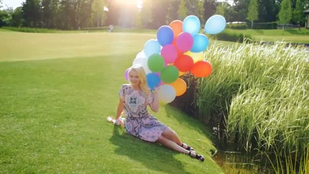 Vídeo em câmera lenta de bela jovem posando balões coloridos junto ao rio — Vídeo de Stock