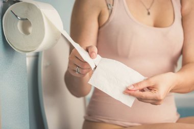 Tuvalette otururken ve tuvalet kağıdı rulosu çekerek genç kadının tonda portre resim