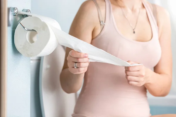 Nahaufnahme einer jungen Frau, die Toilettenpapier abreißt — Stockfoto