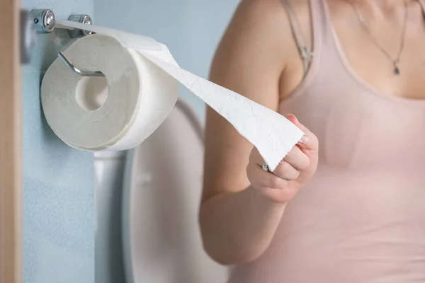 Imagem de close-up da jovem mulher sentada no banheiro e rasgando toalha de papel — Fotografia de Stock