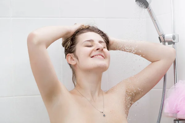 Heureuse femme souriante laver les cheveux sous la douche — Photo