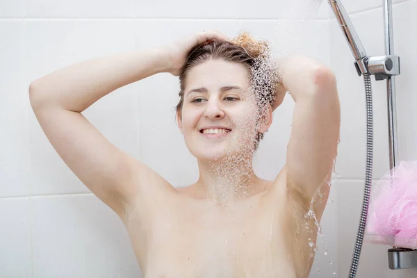 Porträt einer lächelnden jungen Frau, die sich unter der Dusche wäscht — Stockfoto