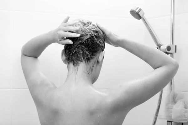 Primer plano foto en blanco y negro de una joven morena lavando el cabello con champú — Foto de Stock