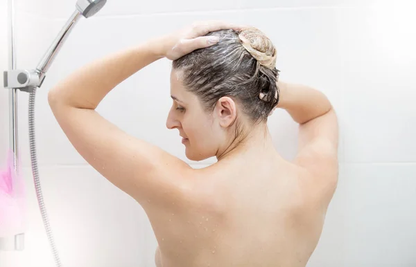 Retrato de una hermosa joven lavando el pelo largo y oscuro en la ducha — Foto de Stock