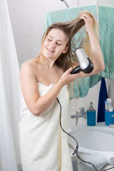 年轻微笑的妇女在洗完澡后烘干长发的肖像 — 图库照片