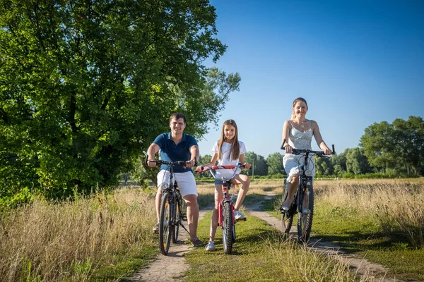 Feliz familia sonriente montar bicicletas en el camino del campo — Foto de Stock