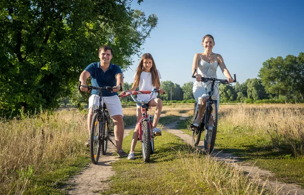 Feliz familia joven montar en bicicleta con el niño en el campo — Foto de Stock
