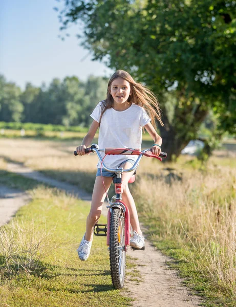 Feliz adolescente con pelo largo montar en bicicleta en el campo en el día soleado — Foto de Stock