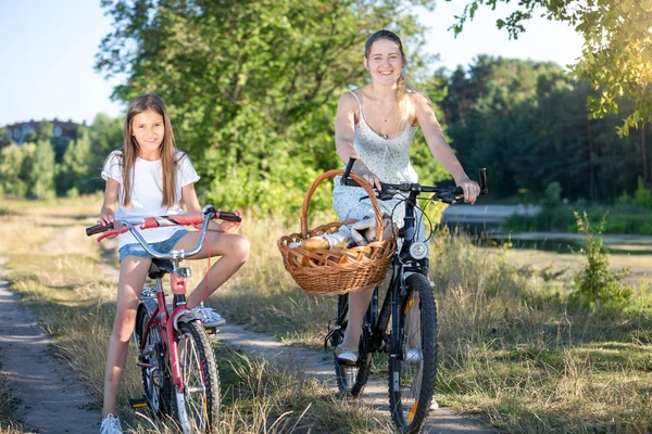 Szczęśliwa młoda matka jazdy na rowerze z nastoletnią córkę w parku — Zdjęcie stockowe