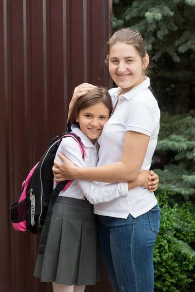 Retrato de madre joven y feliz abrazando a su hija yendo a la escuela —  Fotos de Stock