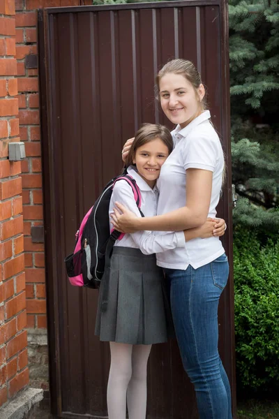 Счастливая молодая мать обнимает свою дочь в школе — стоковое фото
