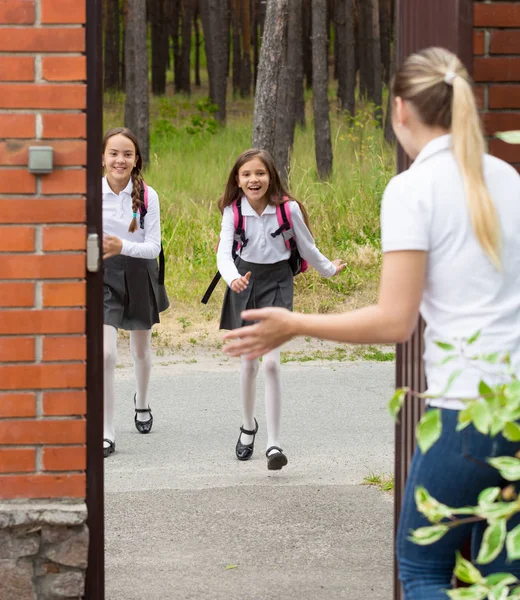 Två glada tjejer som kör till mamma efter skolan — Stockfoto