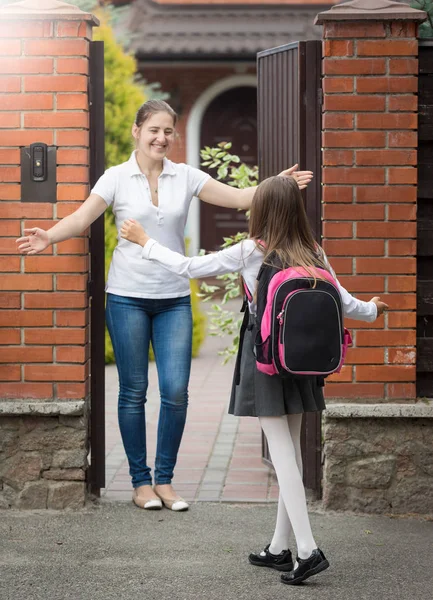 Gelukkig jonge moeder haar dochter knuffelen na school — Stockfoto