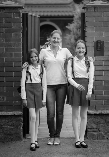 Imagem em preto e branco da família feliz posando na frente da casa grande antes de sair para a escola — Fotografia de Stock