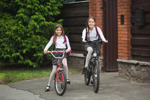 Chicas jóvenes felices montando en bicicletas de casa a la escuela — Foto de Stock