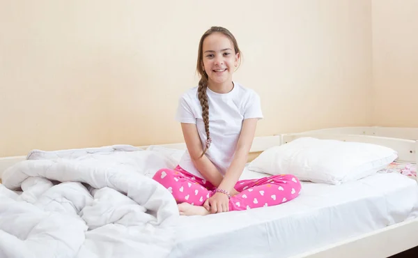 Portret piękne, uśmiechnięte dziewczyny w piżamie, siedząc na łóżku — Zdjęcie stockowe