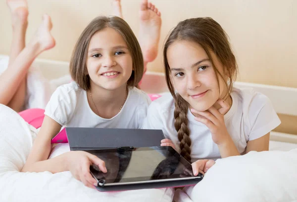 Portrait of beautiful teenage girls lying on bed and holding digital tablet computer — Stock Photo, Image