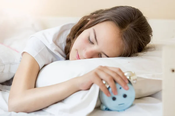 Nahaufnahme Porträt eines Teenagers, der auf dem Bett liegt und den Wecker in der Hand hält — Stockfoto