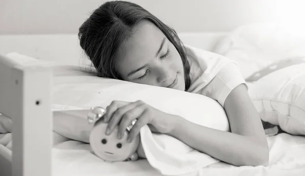 Retrato en blanco y negro de una adolescente durmiendo y apagando el despertador sonando —  Fotos de Stock